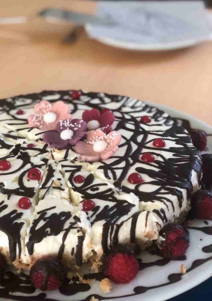 selbstgebackener und liebevoll dekorierter Kuchen mit Himbeeren und Marzipanblüten